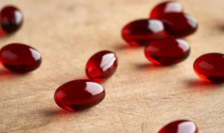 A collection of krill oil softgels laying on a wooden surface