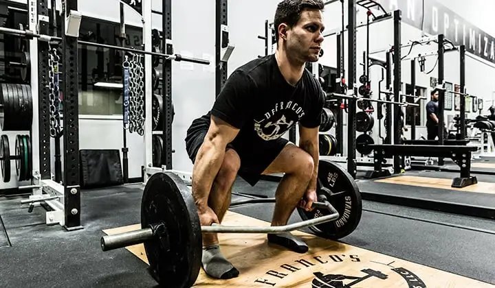 The man in the photo is demonstrating the correct form for hex bar deadlifts. His back is straight and his core is engaged throughout the lift, which helps to protect his spine.