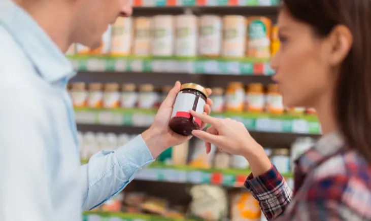 Two people, one holding a capsule bottle and the other pointing to the bottle.