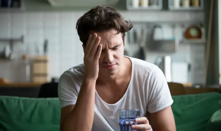 A man with hangover holding a glass of water.