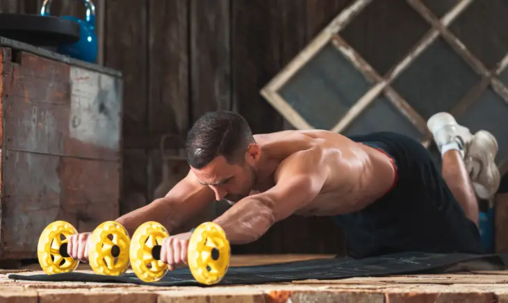 Man doing ab roller exercise, flexing abs and engaging core.