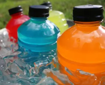 A photo of several electrolyte drink bottles in different colors. The colors of the bottles are red, blue, green and orange.
