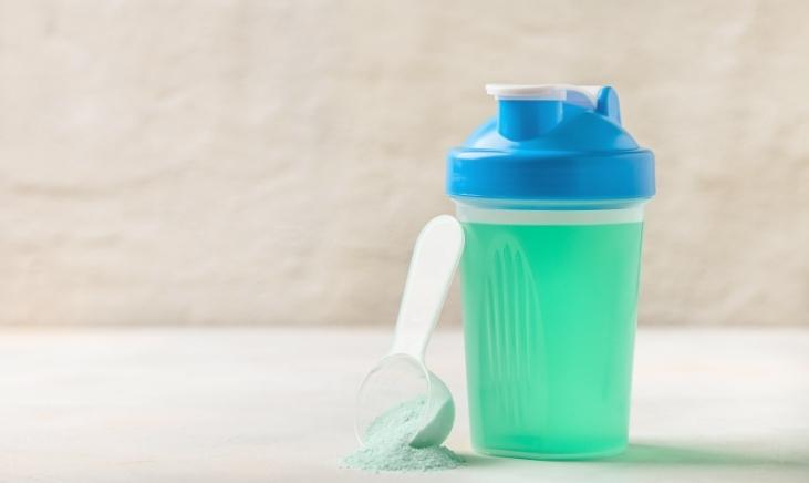 A transparent plastic water bottle filled with green liquid