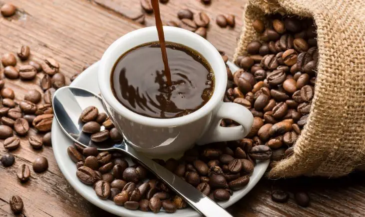 White coffee cup and saucer with coffee beans