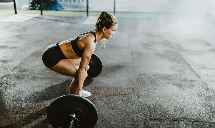 Strong woman lifting a heavy barbell during a deadlift