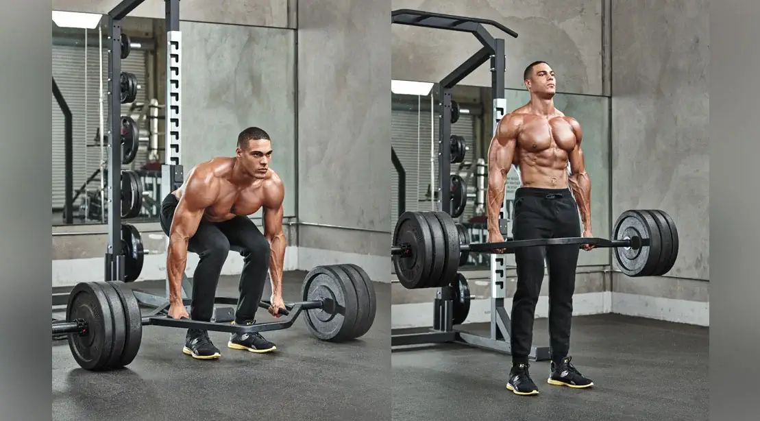 A man demonstrating the top position of a deadlift. He has lifted the barbell to his hips, keeping his back straight and his head up.