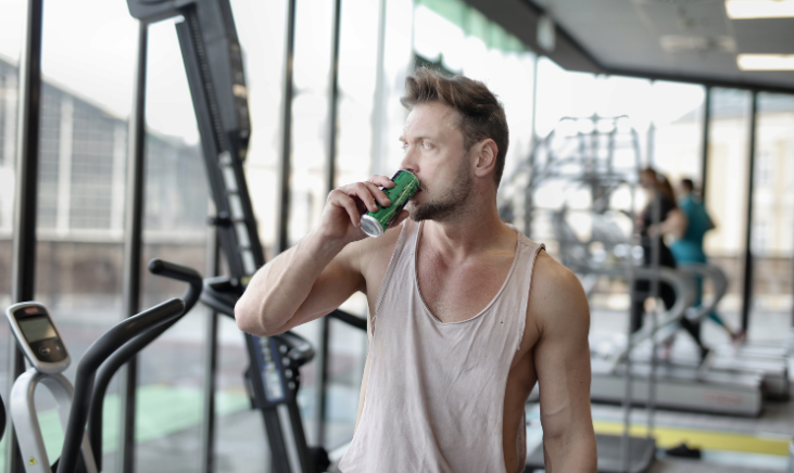 Image of a man taking a break from his workout to drink a sports drink.
