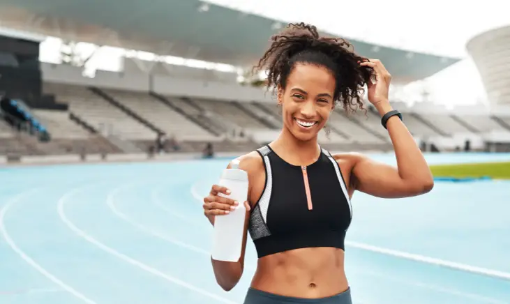 Image of a woman holding a water bottle on a running track.