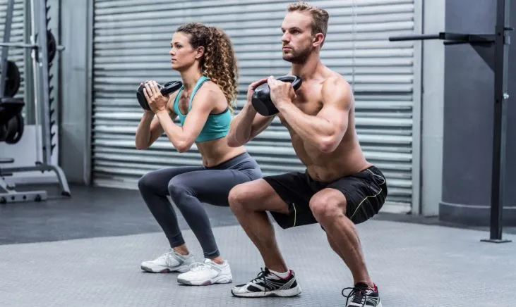 Active couple in workout gear doing lunges together at the gym
