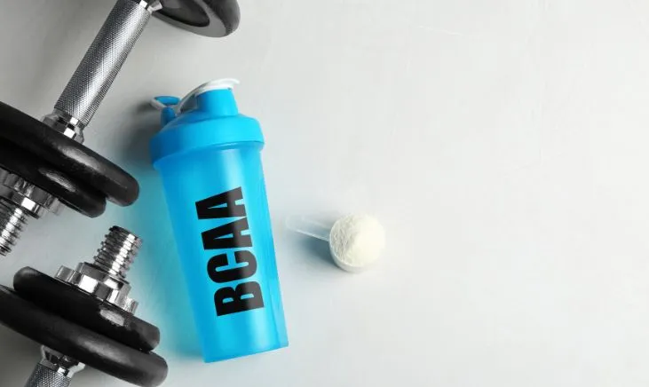 Blue bottle featuring BCAA label surrounded by dumbbells