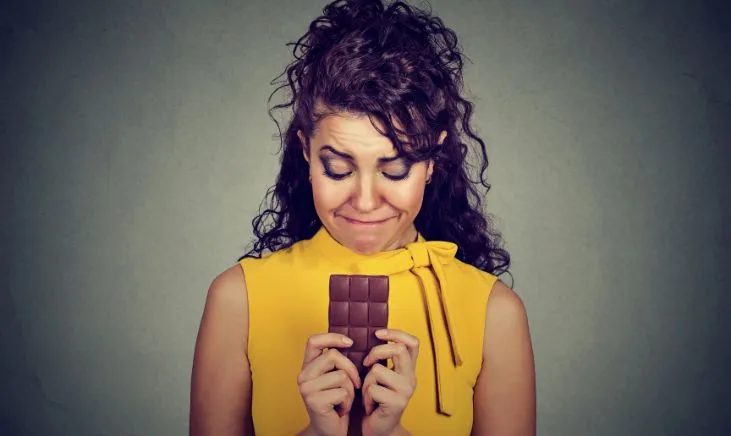 Anxious woman gripping a chocolate treat