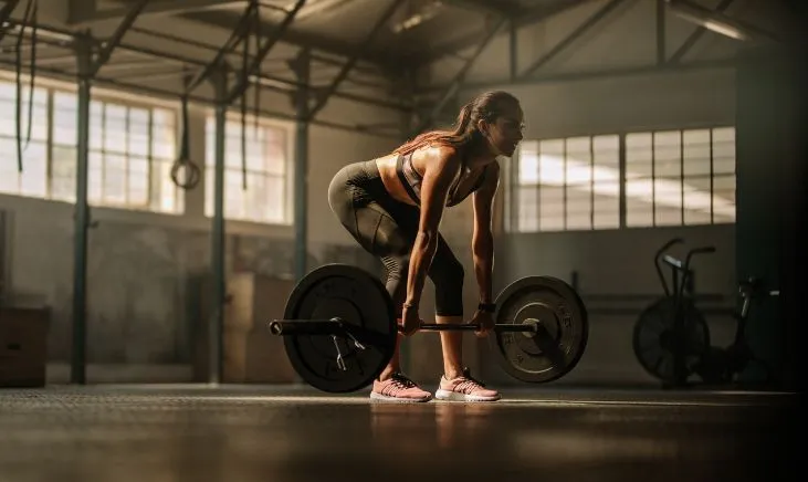 Determined woman lifts heavy barbell