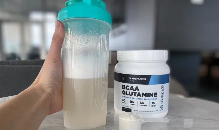 Transparent Labs BCAA Glutamine on table with hand holding bottle