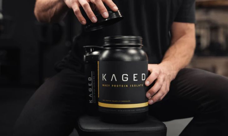 A close-up image of someone holding a tub of Kaged Whey Protein Isolate.